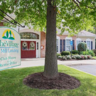 A tree in front of a residential building with a welcoming sign.