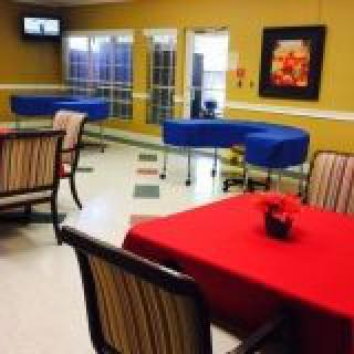 A dining area with tables covered in red cloth and striped chairs, featuring blue furniture and wall decorations.