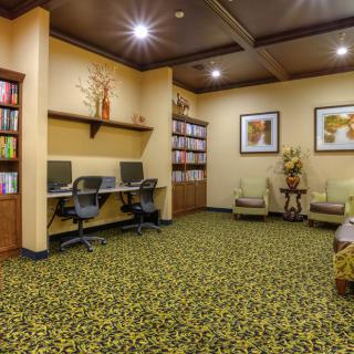 A cozy office space featuring workstations with computers, bookshelves, and comfortable seating.