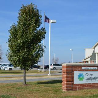 A healthcare facility with an American flag and a tree in the foreground.