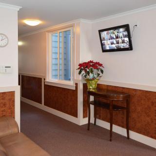 A hallway interior with a small table, plant, wall-mounted television, and window.