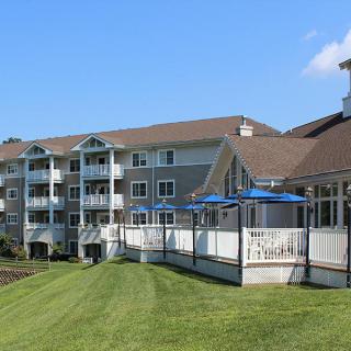 A modern apartment building with balconies and a spacious lawn on a clear day.