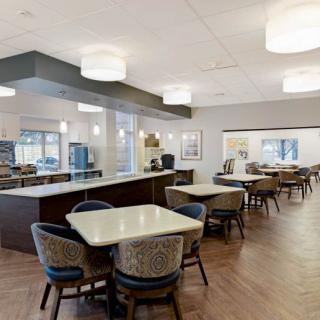 A modern dining area featuring neatly arranged tables and chairs, enhanced by stylish lighting.