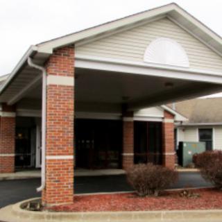 A brick building with a covered entrance and a paved walkway.