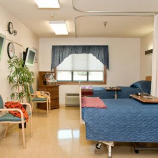 A clean and well-organized hospital room with two beds and seating area.