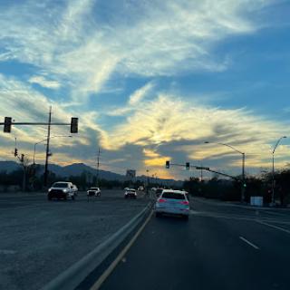 A beautiful sunset captures the sky as cars pass through the intersection.