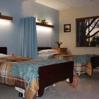 A clean and organized hospital room with two beds separated by a curtain.