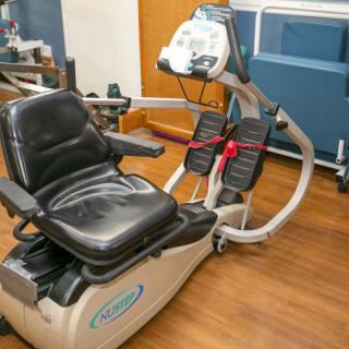 A recumbent exercise bike positioned in a healthcare facility, often used for rehabilitation and fitness purposes.