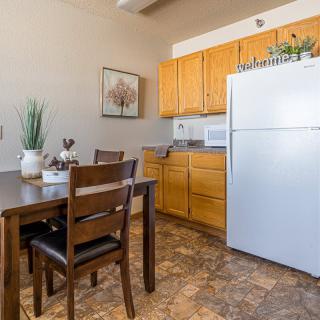 A cozy kitchen and dining area featuring wooden cabinets, a white refrigerator, and a dining table with chairs.