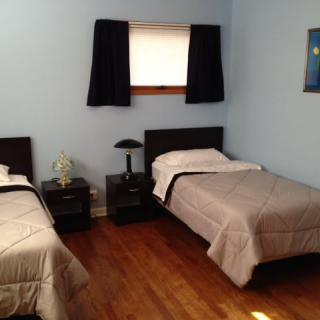 A minimalist bedroom with twin beds and wooden flooring.