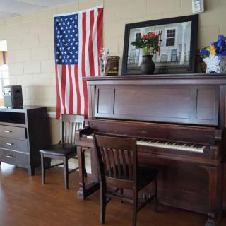 A room with a piano, American flag, and various pieces of furniture.