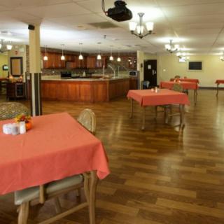 An empty restaurant dining area with tables covered in orange tablecloths and a wooden floor.