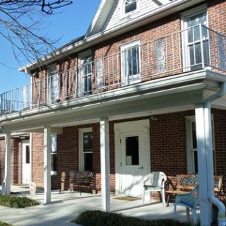A two-story brick house with a covered porch and balcony.