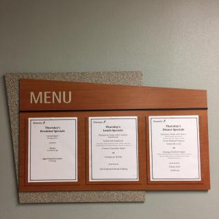 A wall-mounted menu board displaying three sections of printed menus.