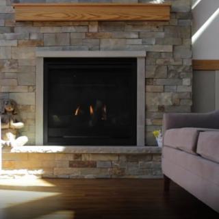 A cozy living room features a stone fireplace with a comfortable couch nearby.