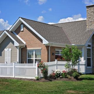 A beautiful single-story house with a white fence and a well-maintained garden.