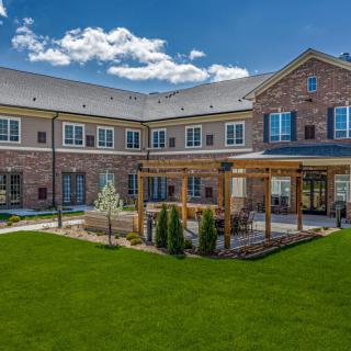 A brick building with a well-maintained lawn and garden area under a clear blue sky.