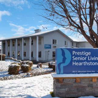 A snowy day at Prestige Senior Living Hearthstone, showcasing the building and its sign.