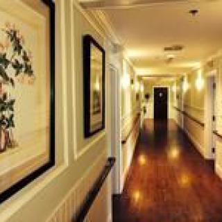A well-lit hallway with framed artwork and wooden flooring.