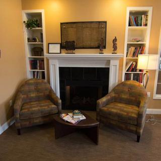 A cozy living room with two armchairs, a fireplace, and bookshelves.