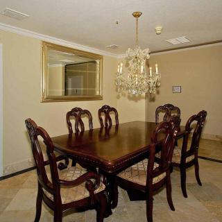 A traditional dining room with a wooden table and chairs, accented by a chandelier and large mirror.