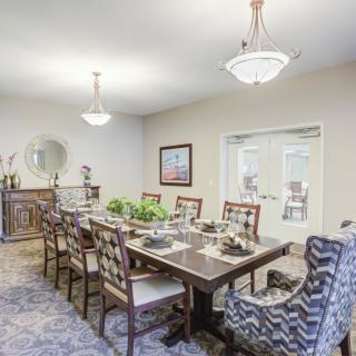 A well-decorated dining room with a large table and elegant chandeliers.