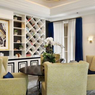 Elegant living room with a dining area, featuring plush chairs, a round table, and a built-in wine rack.