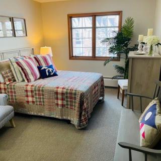 A cozy bedroom with a neatly made bed, colorful pillows, and warm lighting.