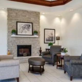 A cozy living room with a stone fireplace, surrounded by comfortable armchairs and modern decor.