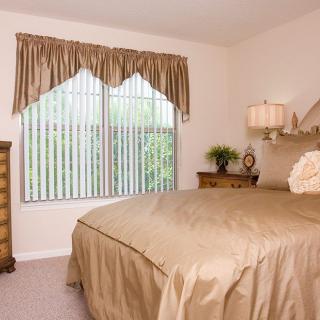 A cozy bedroom with a large bed, wooden furniture, and a window with curtains.