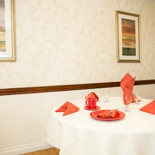 A beautifully set dining table with red accents against a cream-colored wall, featuring decorative artwork.