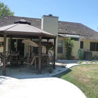 A cozy backyard with a gazebo and patio area, featuring outdoor furniture.