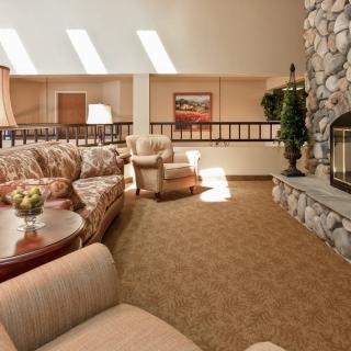 A cozy living room with plush seating, a stone fireplace, and ample natural light.