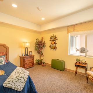 A cozy bedroom with warm lighting, featuring a bed, lamp, and decorative items.