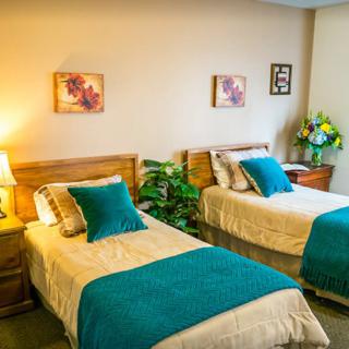 A cozy bedroom with twin beds, teal accents, and warm lighting.