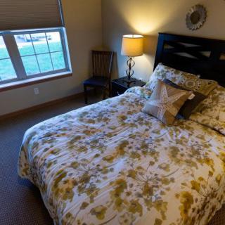 A cozy bedroom with floral bedding and a warm lamp by the window.