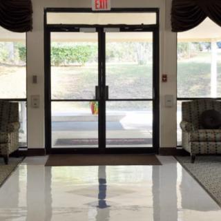 A well-lit lobby entrance with glass doors, flanked by two patterned chairs.