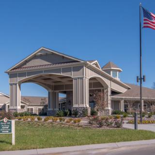 A building with a grand entrance and an American flag waving in the foreground.