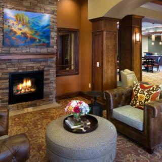 A cozy living room with a brick fireplace, comfortable seating, and decorative artwork.