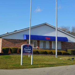 A community building with a blue awning and a sign out front on a clear day.