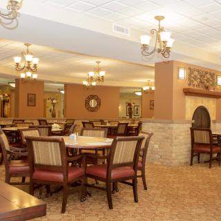 A spacious and elegantly decorated dining room with tables and chairs arranged neatly under chandeliers.