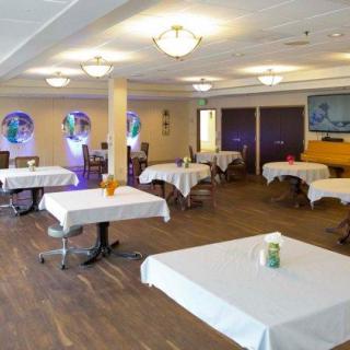A spacious dining area with neatly arranged tables and chairs, covered with white tablecloths.