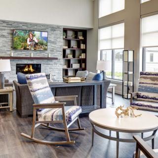 A modern living room featuring a fireplace, cozy rocking chairs, and large windows.