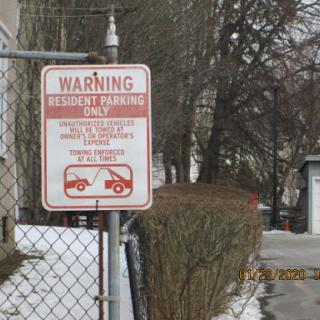 A warning sign indicating that parking is restricted to residents only and unauthorized vehicles will be towed.