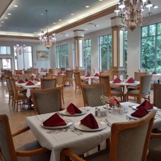 An elegantly set dining room with neatly arranged tables and chandeliers.