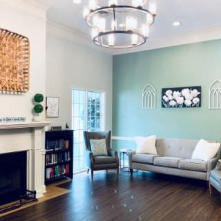 A modern living room with a cozy fireplace, elegant chandelier, and comfortable seating.