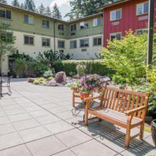 A peaceful courtyard with benches and lush greenery in an apartment complex.