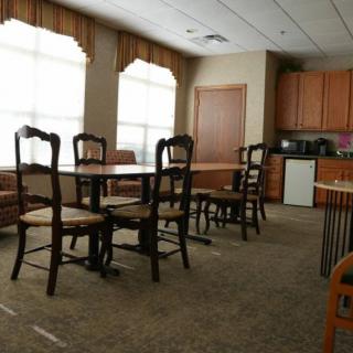 A dining area with wooden chairs and tables, adjacent to a small kitchen.