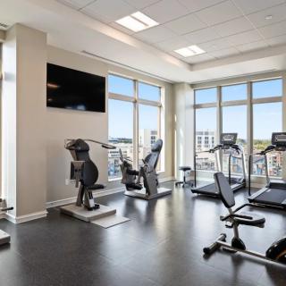 A modern gym with large windows, featuring exercise equipment like treadmills and bikes.