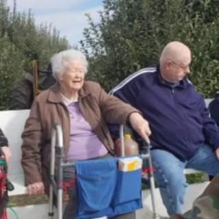 A group of elderly people sitting outdoors, enjoying the company of each other.